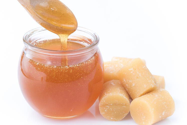 Jaggery syrup in a bowl with jaggery pieces next to it