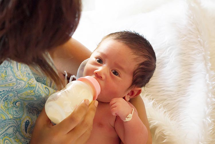 A mother feeding her little baby.