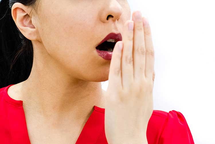 A young lady checking her breath.