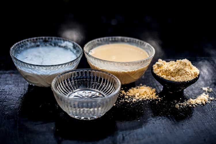 Curd and gram flour placed in separate glass bowls.