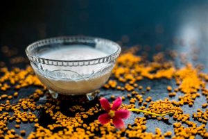 Curd in a glass bowl placed on a table along with pink flower.