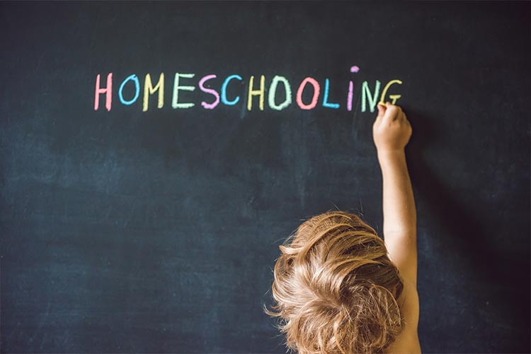 A boy writing 'Homeschooling in India' on a black board.