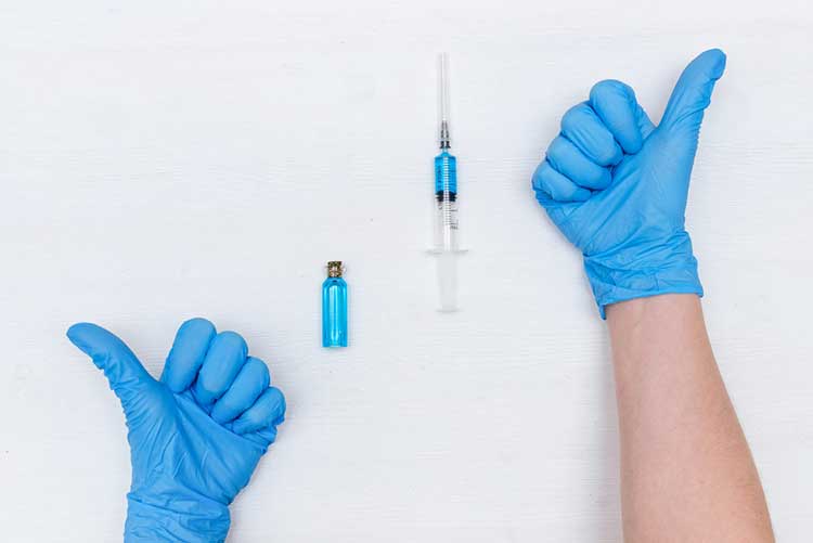 Gloved hands giving thumbs up to an injection