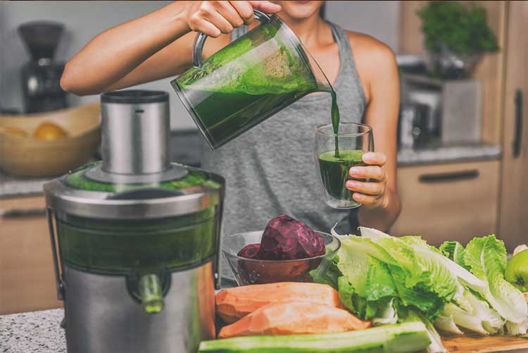 Woman pouring vegetable juice into a glass from a blender