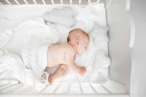 A baby fast asleep in its crib.