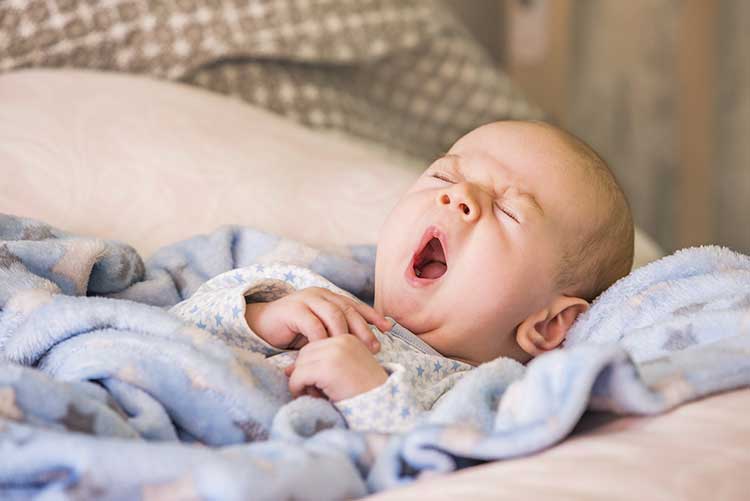 A baby yawning after a good night's sleep.