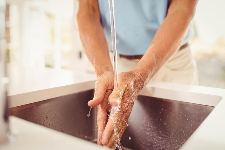 A man washing his hands before holding his baby.