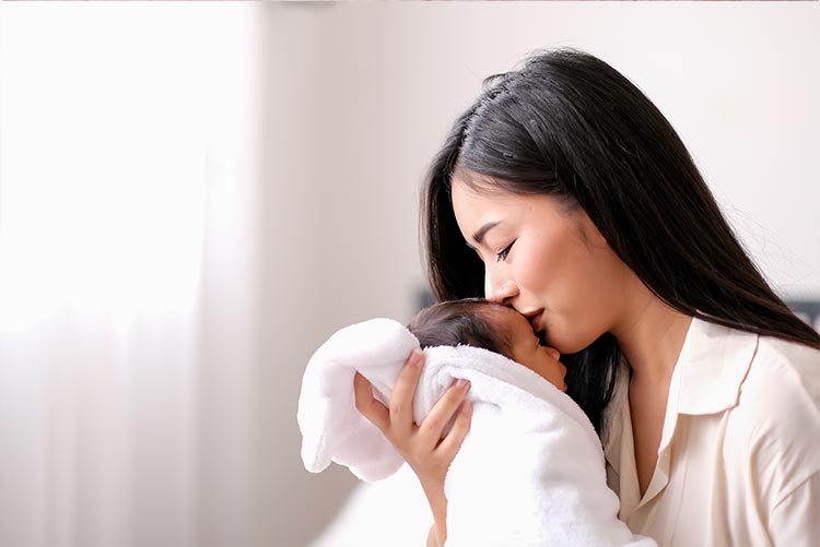 A mother kissing her newborn.