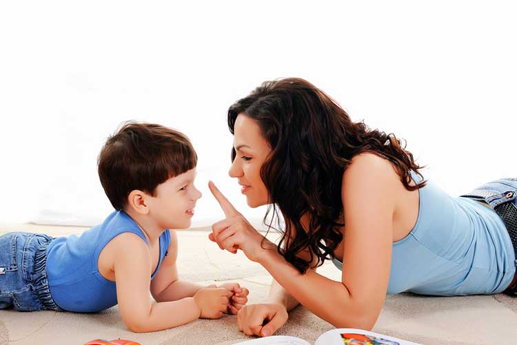 Mother and her son having a playful conversation lying on the floor.