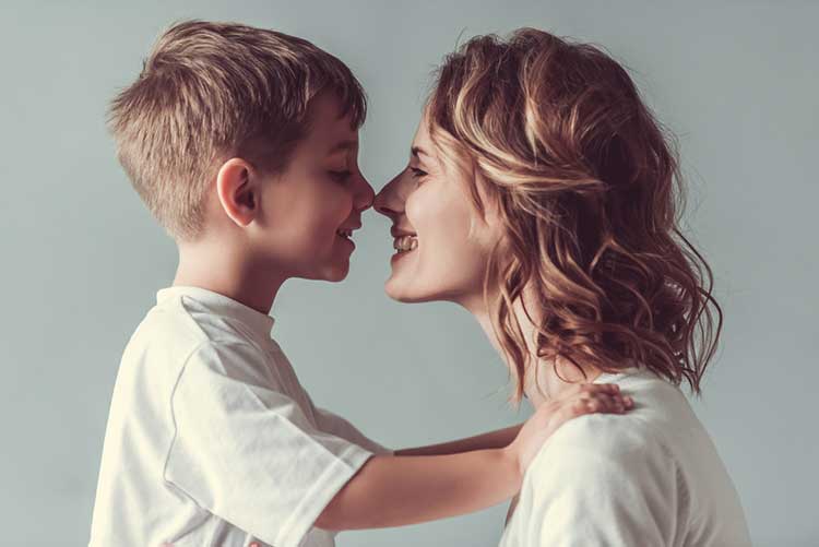 Mother and son touching their noses and smiling.