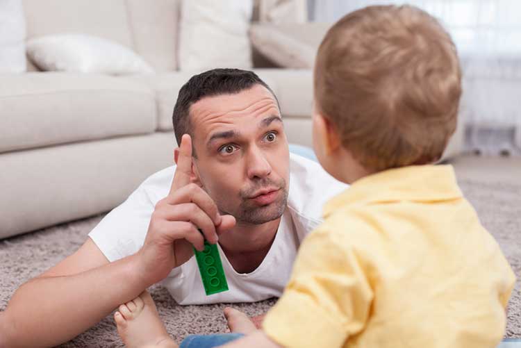 Father explaining something to his toddler while raising a finger.