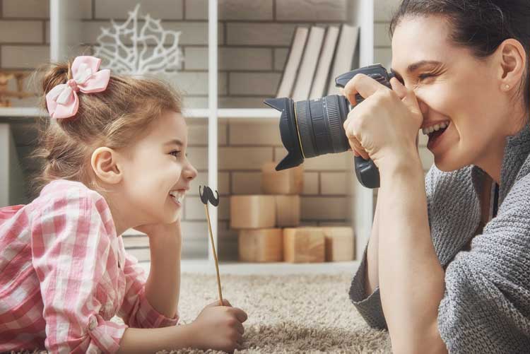 A mother clicking a picture of her daughter.
