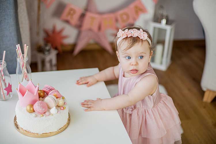 A girl standing her her birthday cake.