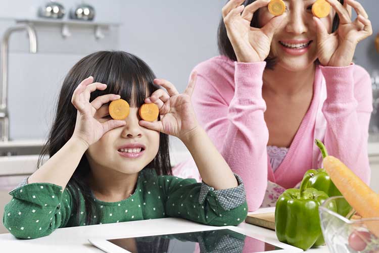 Mom and daughter holding carrot slices near their eyes