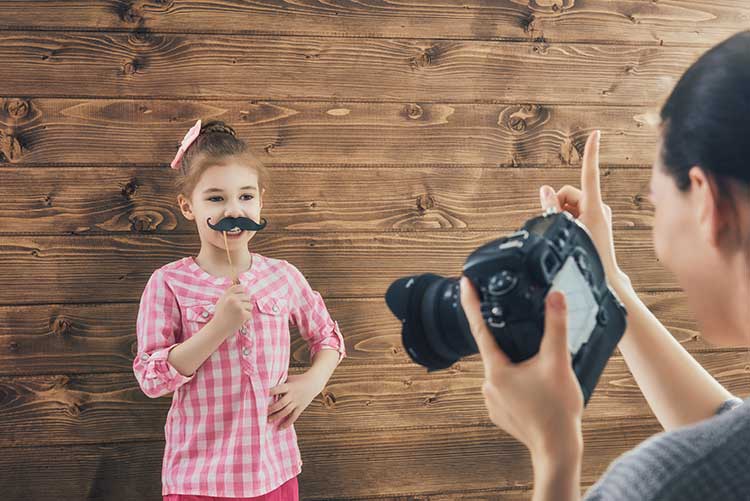 A girl holds a moustache prop at a photoshoot.