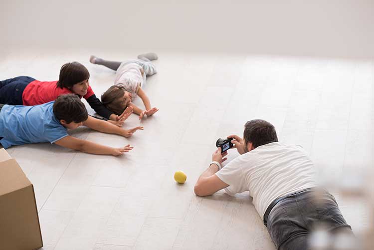 Kids posing for the camera while their dad clicks a picture.